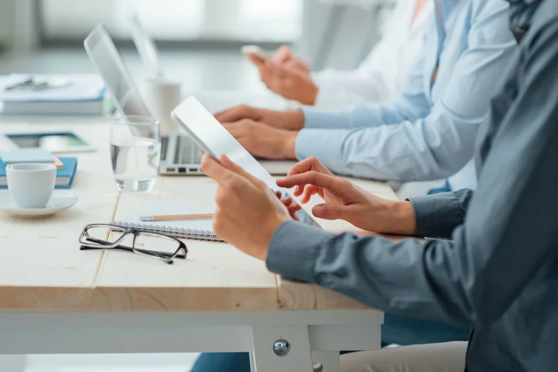 Colleghi al lavoro con tablet e portatili attorno a un tavolo