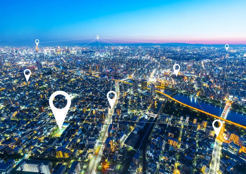 Veduta aerea notturna di una citta con i segnaposto della geolocalizzazione
